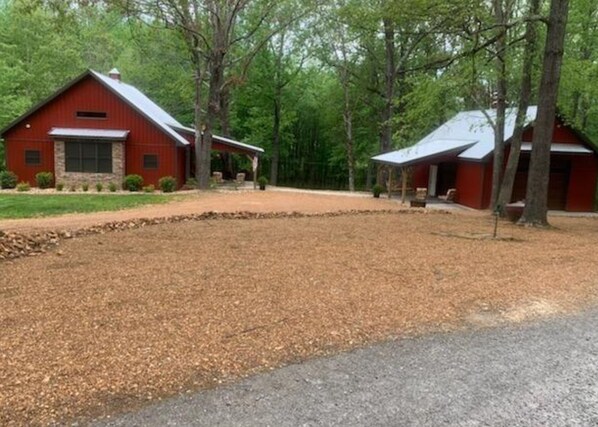 A red barn with a stone foundation, a covered porch, and a gravel driveway.
