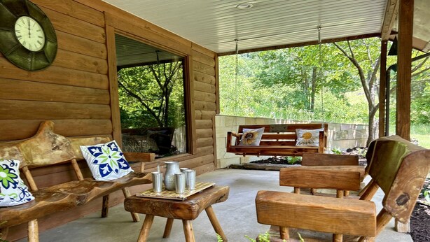 A wooden cabin with a porch, furnished with a bench, a wooden chair, and a small table with a pitcher and cups. - Secluded Hillside Cabin on Historic working Farm (Lampe)