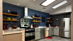 A modern kitchen with stainless steel appliances, wooden shelves, and a red rug. - Secluded Hillside Cabin on Historic working Farm (Lampe)