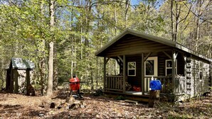 Una cabaña rústica con un porche, rodeada de un bosque.