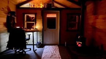 A cozy cabin with a wooden interior, a fireplace, and a table with bottles.