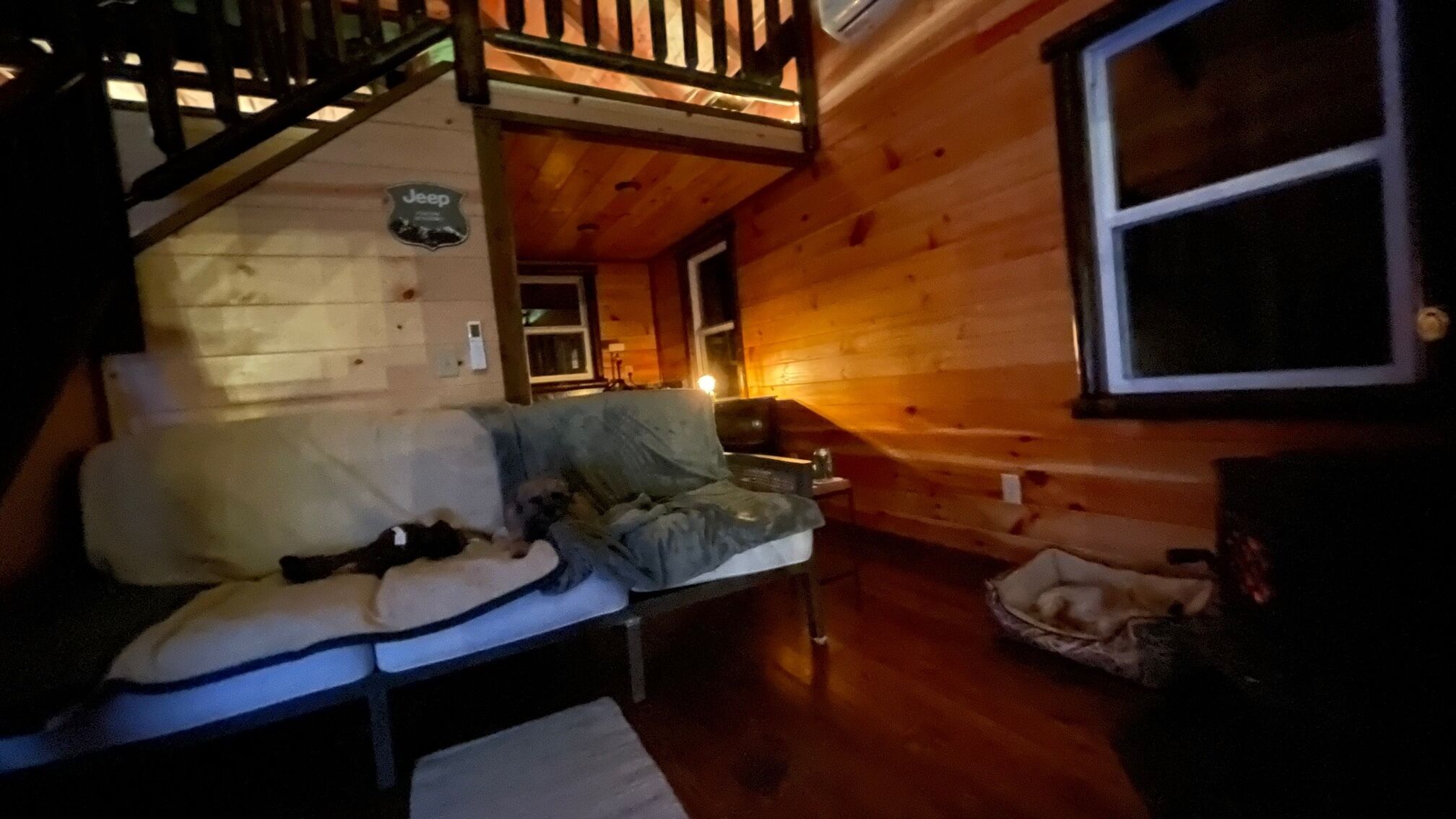 L’intérieur d’un chalet accueillant, avec un escalier en bois, un canapé, une petite table et une fenêtre.
