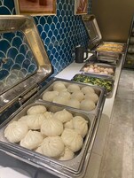 Un buffet con diversi cibi, tra cui gnocchi, uova e verdure.