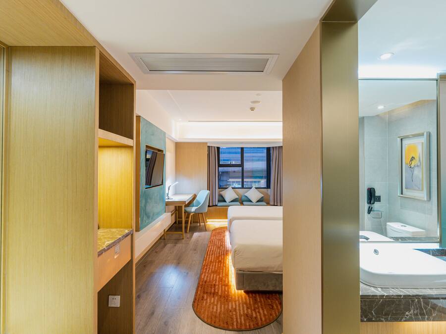 Une chambre d’hôtel comprenant un lit, un bureau, une chaise et une salle de bain avec des toilettes et un lavabo.