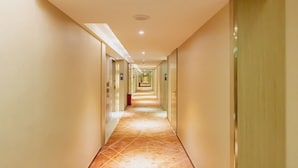 A long, well-lit hallway with a patterned floor, leading to multiple doors on either side. - K-house Hotel (Guangzhou)