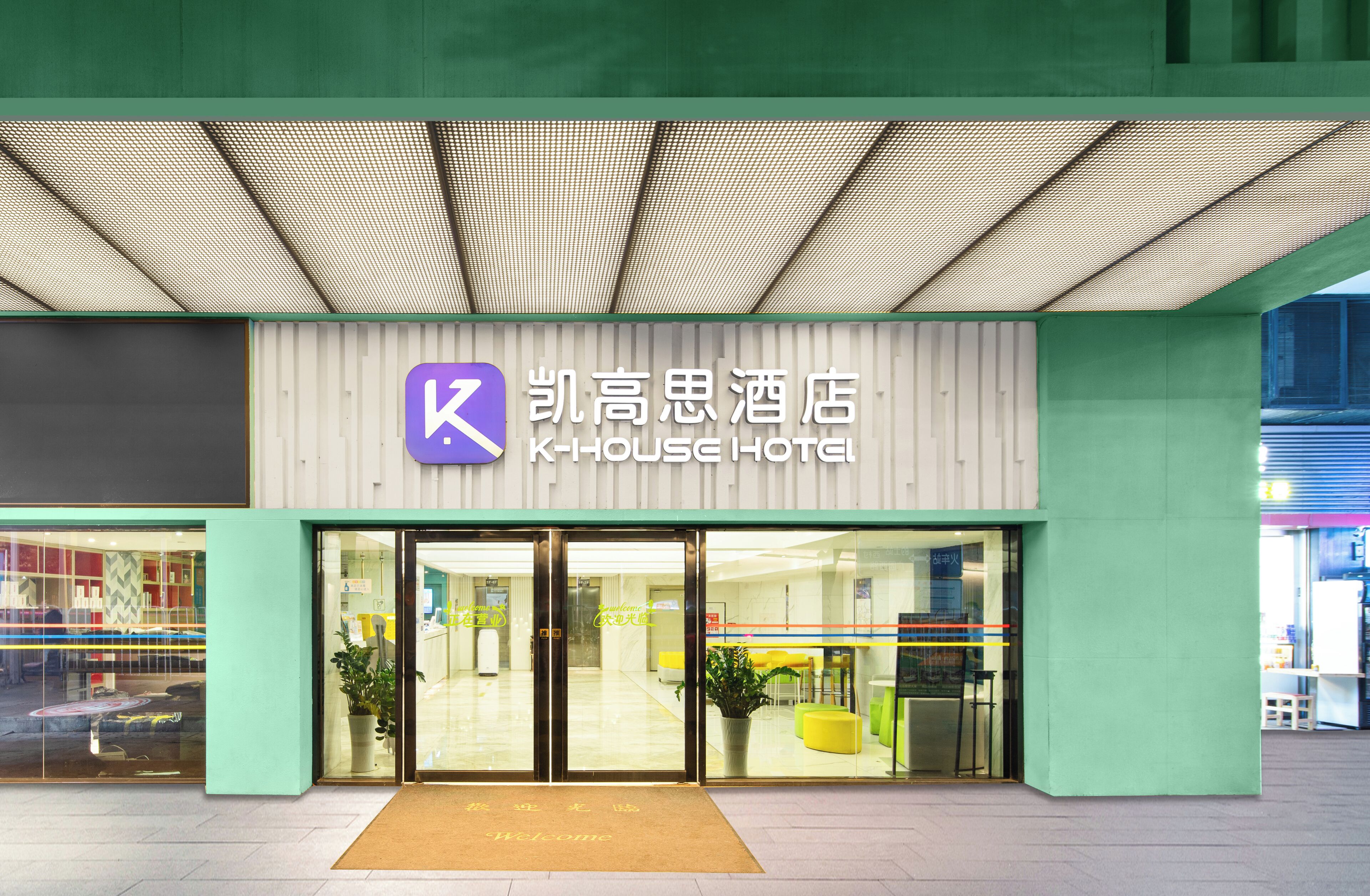 The exterior of K-HOUSE HOTEL with a modern design, featuring a prominent 'K' logo, large glass doors, and a welcoming entrance.