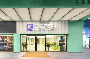 The exterior of K-HOUSE HOTEL with a modern design, featuring a prominent 'K' logo, large glass doors, and a welcoming entrance.