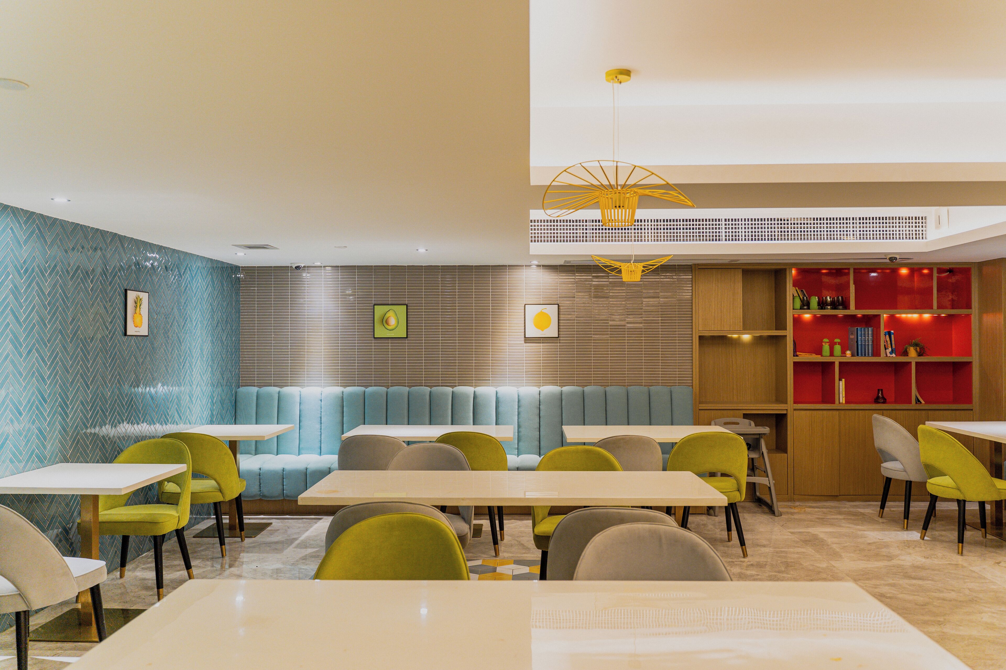 Un restaurant avec des banquettes, des tables et des chaises. On y trouve une bibliothèque avec des livres et des objets décoratifs.