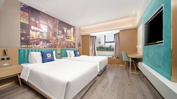 A hotel room with two beds, a desk, a TV, and a large cityscape mural on the wall.