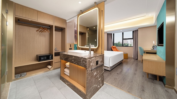 A modern hotel room with a marble bathroom vanity, a bed, a desk, and a view of the city. - K-house Hotel (Guangzhou)