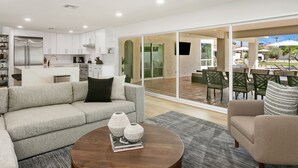 A modern living room with a sofa, coffee table, and a view of the outdoor patio area. - SWSS 8BR Palms Away Estate | Pool, Hot Tub, Sport Court, Putting Green & Games (Scottsdale)