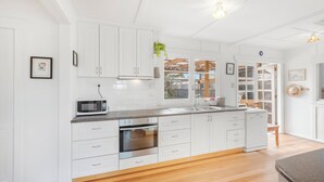 A modern kitchen with white cabinetry, a built-in oven, and a microwave. - Mandalay on Pipeclay - 3 Bedroom House - Free Parking - Free WIFI (Cremorne)