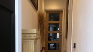 A hallway with wooden flooring, a white door, and a large vase with tall grasses. - Two Bedroom House, Birchington, ct79rn (Birchington)