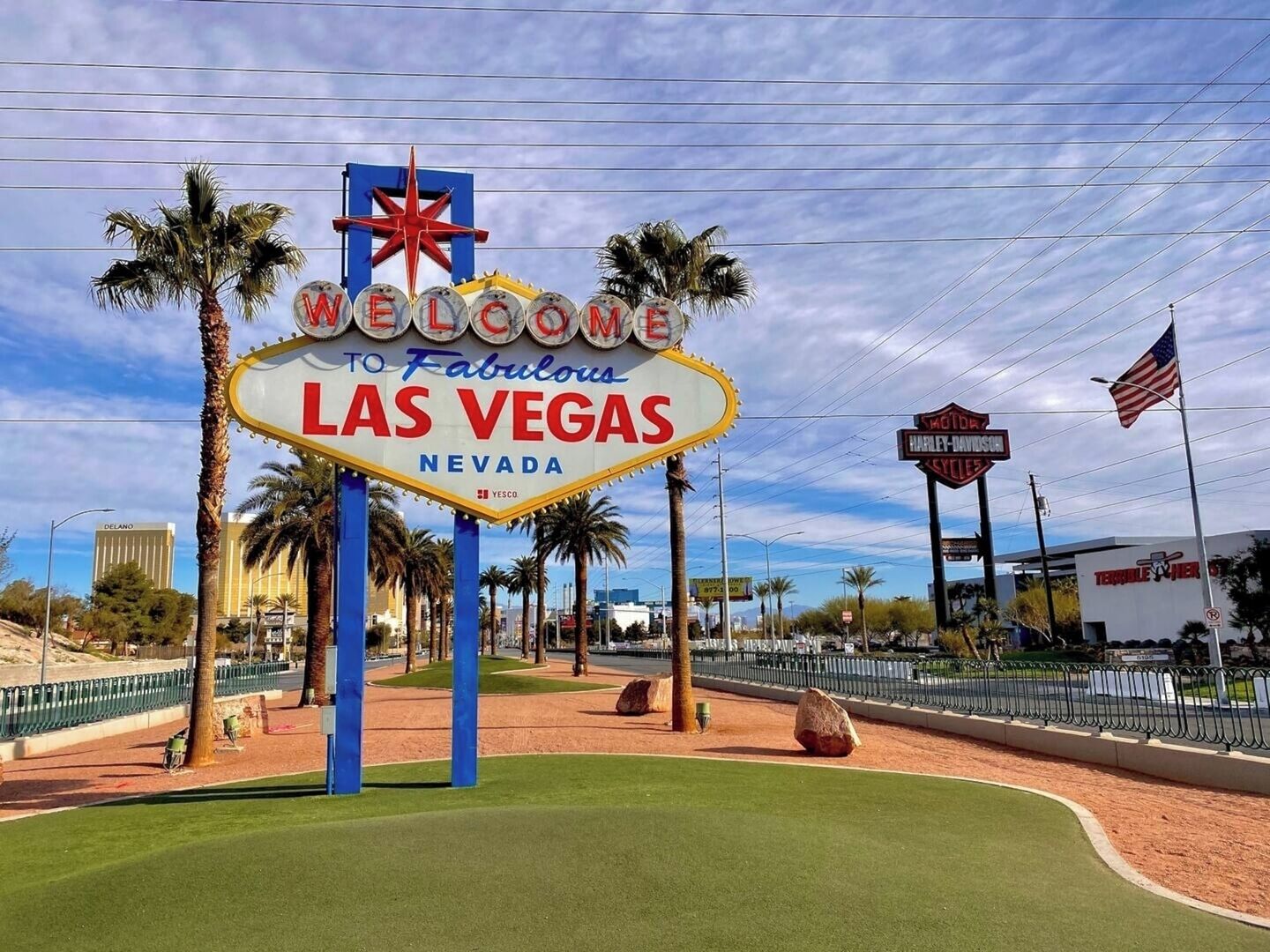 A 'Welcome to Fabulous Las Vegas Nevada' sign with palm trees and a fence in the foreground.