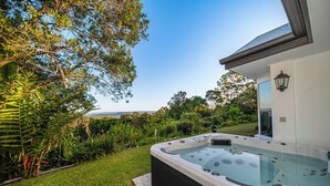A hot tub in a lush garden with a view of the landscape.
