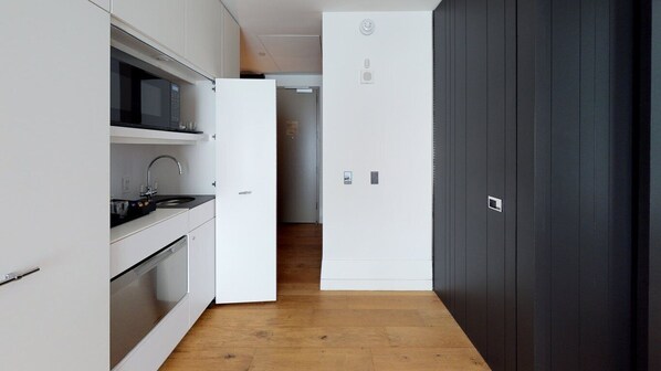 A modern kitchen with white cabinetry, a microwave, and a refrigerator.