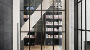 Un interior moderno con una escalera que conduce a una estantería llena de libros.