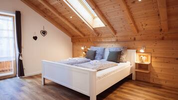 A bedroom with a wooden ceiling, a bed with patterned bedding, and a nightstand with a lamp.