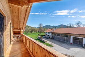 En træbalkon med udsigt over en garage og en bygning med rødt tag.