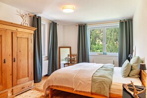 A bedroom with a wooden wardrobe, a bed with green bedding, a window with curtains, and a view of greenery outside. - Holiday Home 'Maierhof 341' with Lake View, Private Terrace and Wi-Fi (See)
