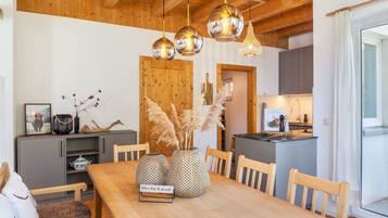 A wooden dining table with three spherical vases, a wooden bench, and a kitchen area with a wooden door and cabinets.