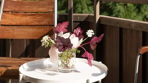 A round white table with a vase of flowers on a balcony.