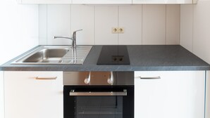 A modern kitchen with white cabinets, a stainless steel sink, and a built-in oven.