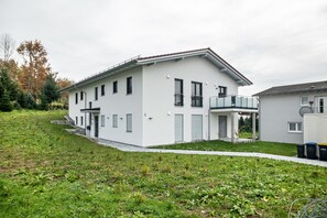 Uma casa moderna de dois andares com varanda, um pequeno alpendre e garagem.