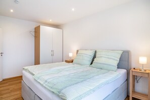 Une chambre à coucher comprenant un lit, des tables de chevet, une armoire et une lampe de chevet.