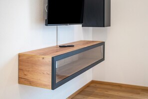 A wall-mounted TV on a wooden console with a remote control. - Apartment 'Fichte' with Balcony and Wi-Fi (Ravensburg)
