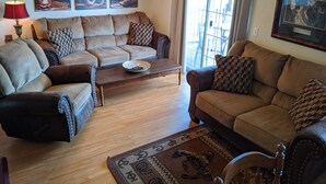 Una sala de estar con un sofá de cuero marrón, una mesa de centro de madera y un tapete estampado.
