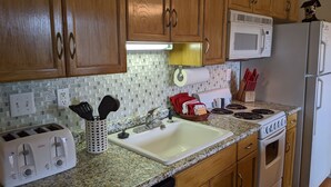 Una cocina con armarios de madera, microondas, estufa, lavaplatos y tostadora.