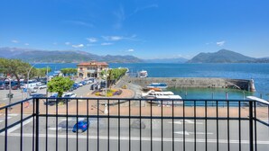 Un port de plaisance sur la côte, avec des bateaux, un bâtiment doté d’un toit rouge et des montagnes en arrière-plan.
