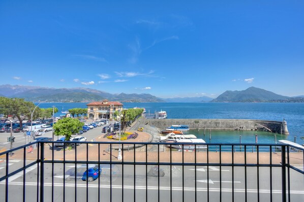 Un port de plaisance sur la côte, avec des bateaux, un bâtiment doté d’un toit rouge et des montagnes en arrière-plan.
