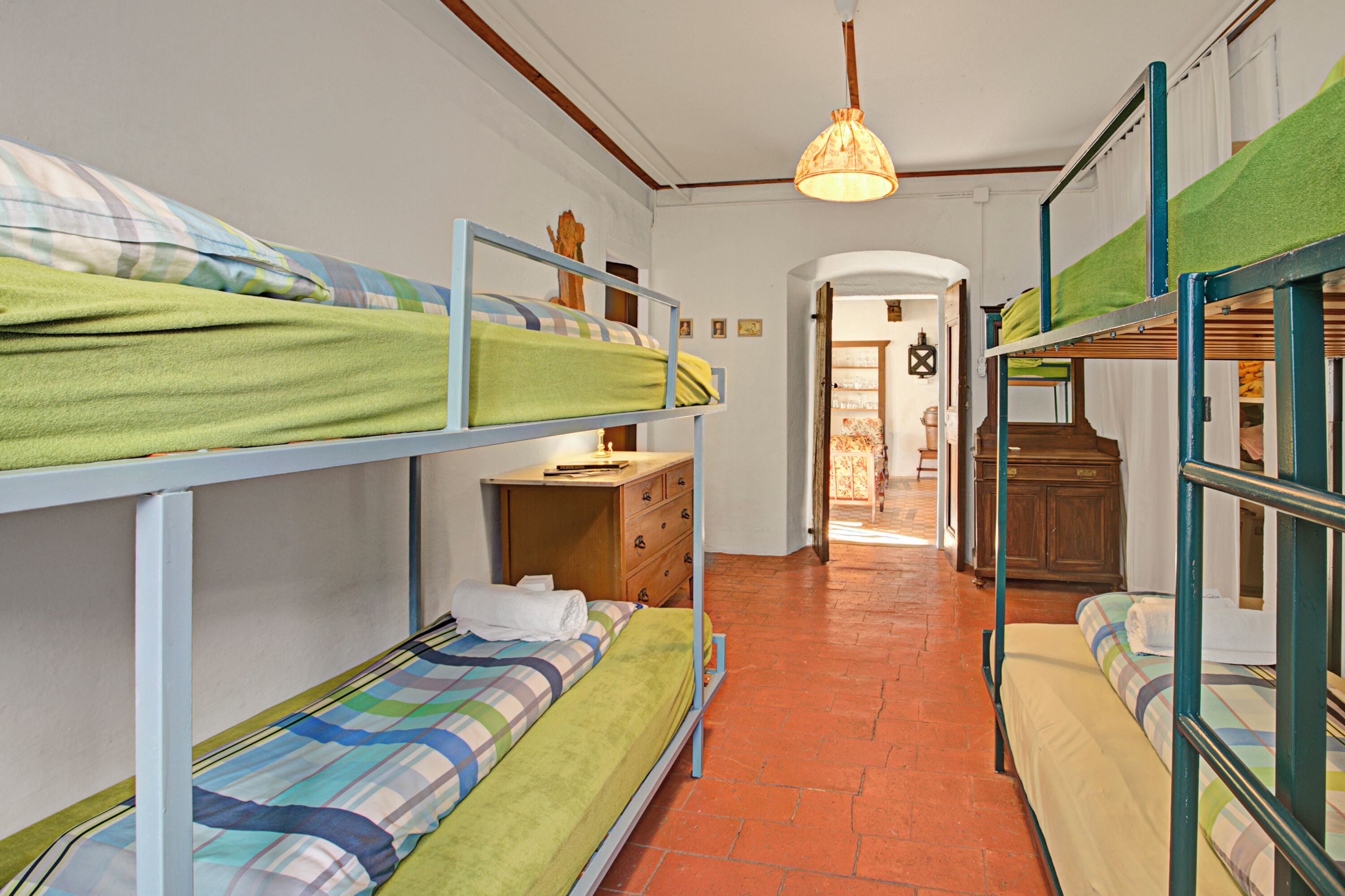 Un dormitorio con literas, un aparador de madera y un pasillo que conduce a otra habitación.