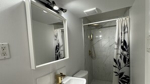 Ein modernes Badezimmer mit Waschbecken, Toilette und Dusche, alles in Weiß.