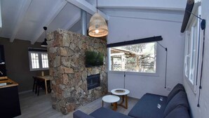 A modern living room with a stone fireplace, a flat-screen TV, a sofa, and a dining area. - House Palmito 2, Chiclana de la Frontera (Chiclana de la Frontera)