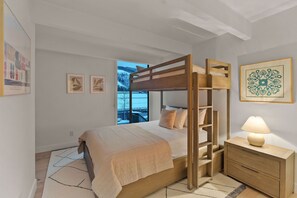 Un lit superposé avec une structure en bois et une table de chevet avec une lampe.