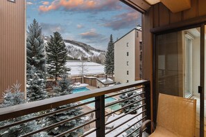 Un balcon donnant sur un paysage enneigé, une piscine et un immeuble à plusieurs étages.
