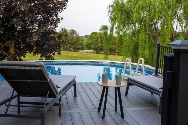 Terraza con sillones de descanso y una mesa con vista a una piscina.