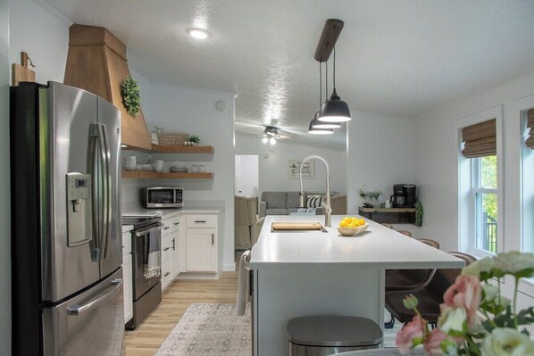 Una cocina moderna con una isla central, electrodomésticos de acero inoxidable e iluminación colgante.