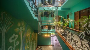 A multi-level atrium with a spiral staircase, green walls, and potted plants. - Kandy Dendrobium House (Puliyadda)