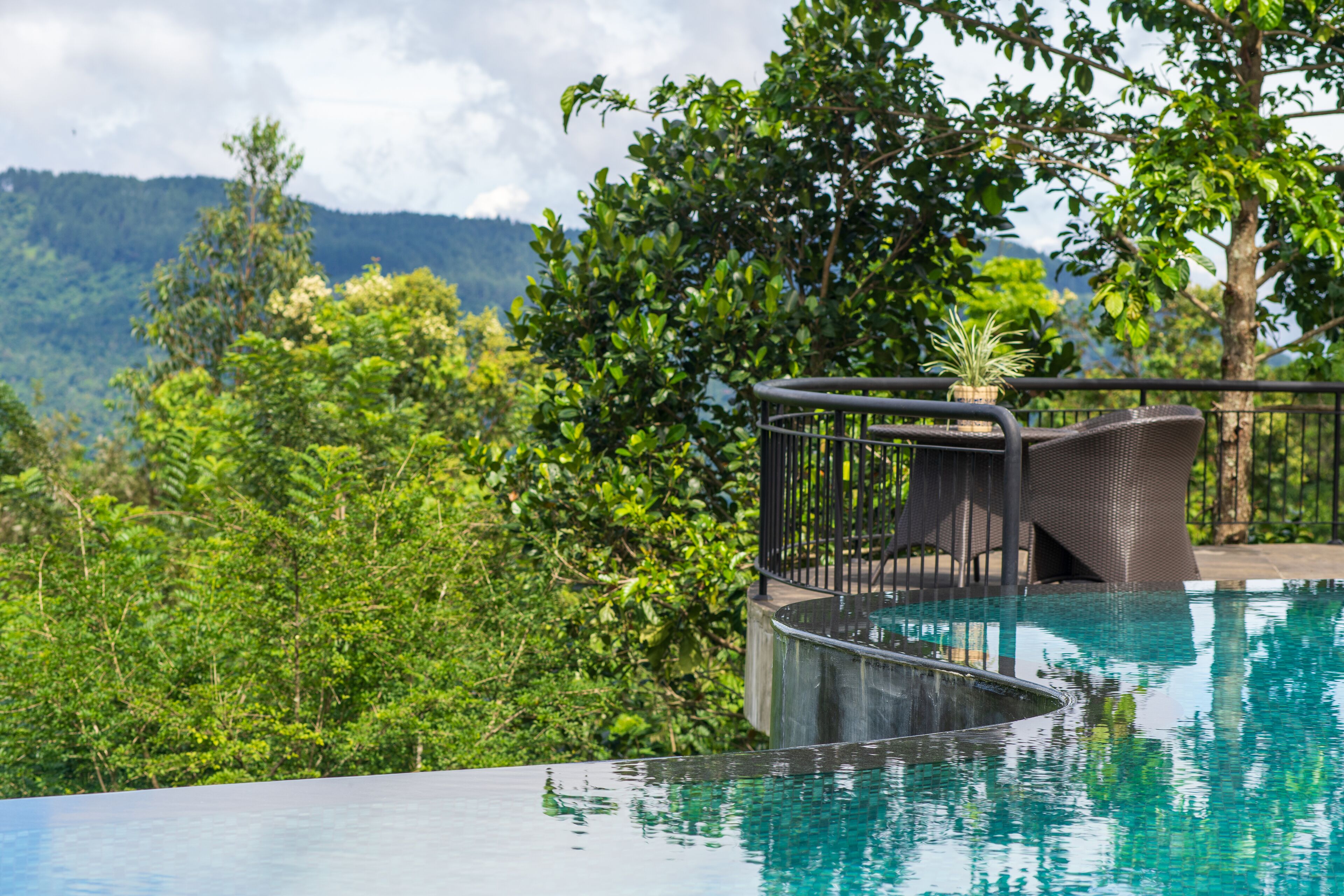 Una piscina de borde curvo, rodeada de exuberante vegetación y vistas a montañas distantes.