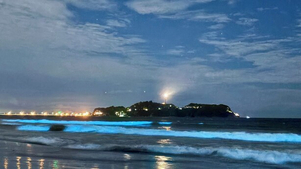A beach with waves, a distant illuminated structure, and a cloudy sky. - kishu railway katase enoshima hotel (Fujisawa)