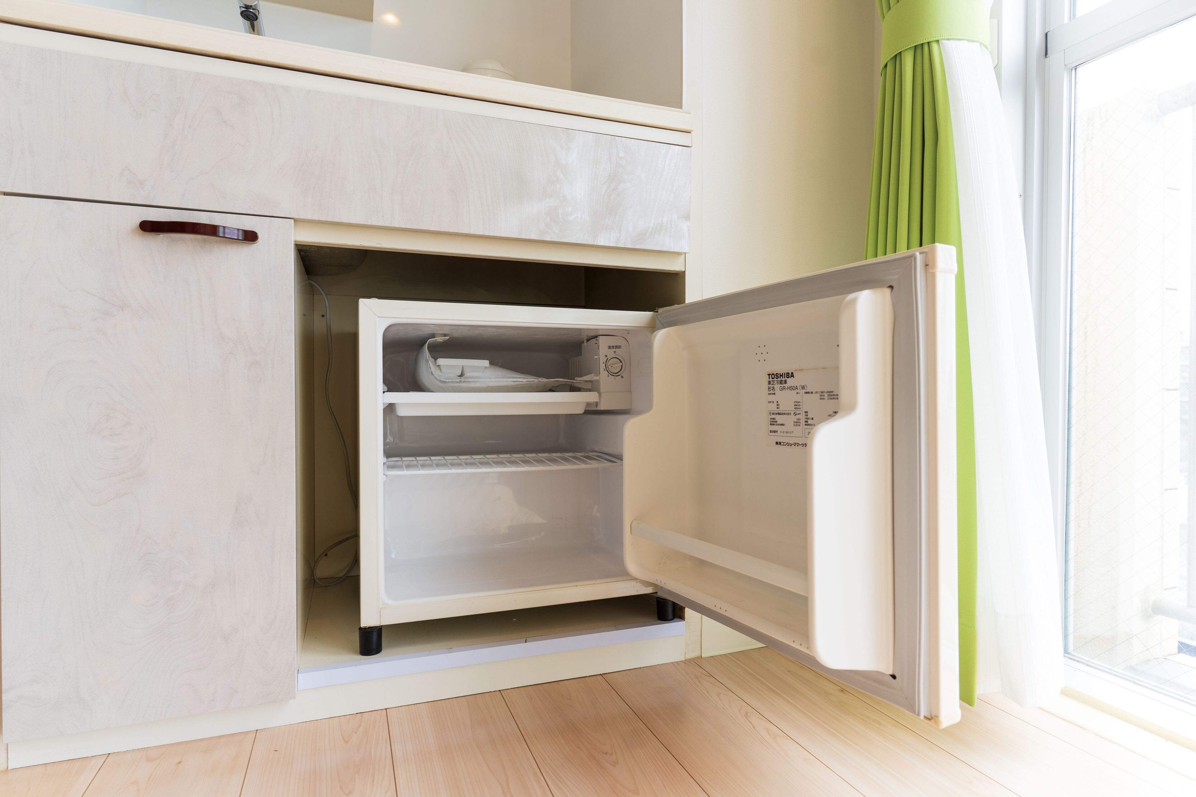 Un refrigerador compacto con compartimento congelador, integrado en un mueble de cocina.
