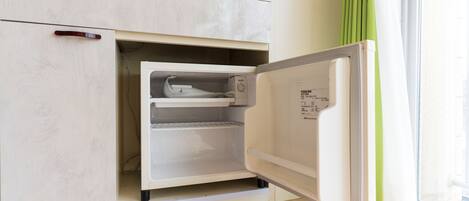 Un refrigerador compacto con compartimento congelador, integrado en un mueble de cocina.