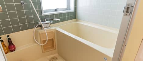 Un baño con bañera, ventana y ducha.