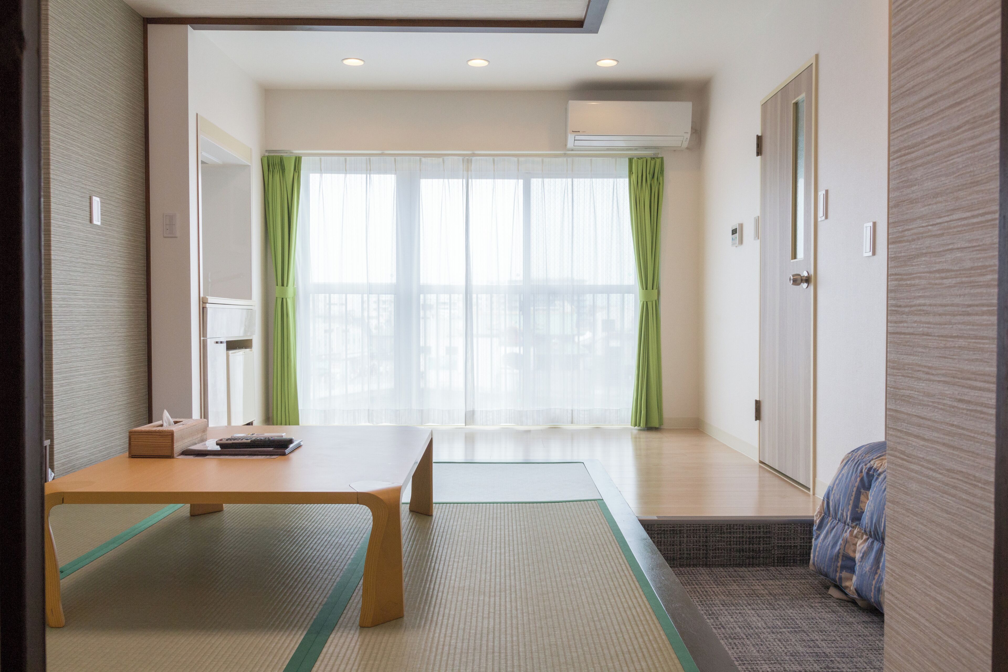 Une pièce dotée d’un sol recouvert de tatamis, d’une table en bois, d’un futon servant de lit et d’une porte coulissante.