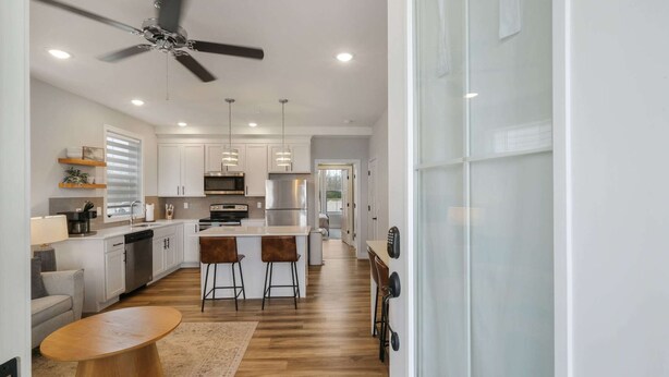 A modern kitchen with white cabinets, stainless steel appliances, and a central island with bar stools. - Mansion Flat @ Navvy Town (Ottawa)