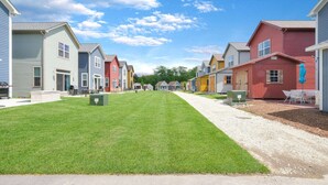 A row of colorful single-story houses with a well-maintained lawn and gravel driveway. - Mansion Flat @ Navvy Town (Ottawa)